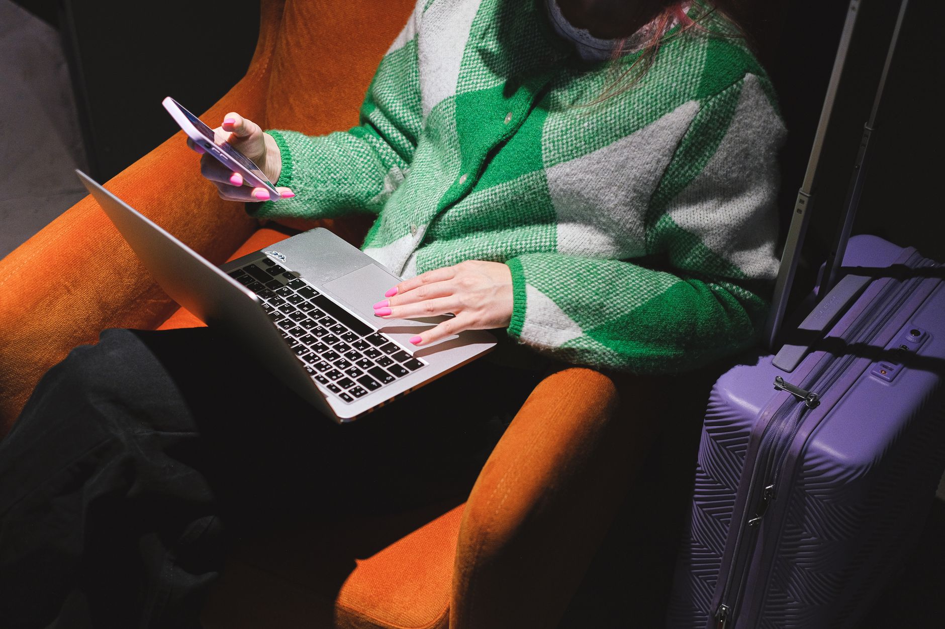Person using a laptop and phone away from a desk