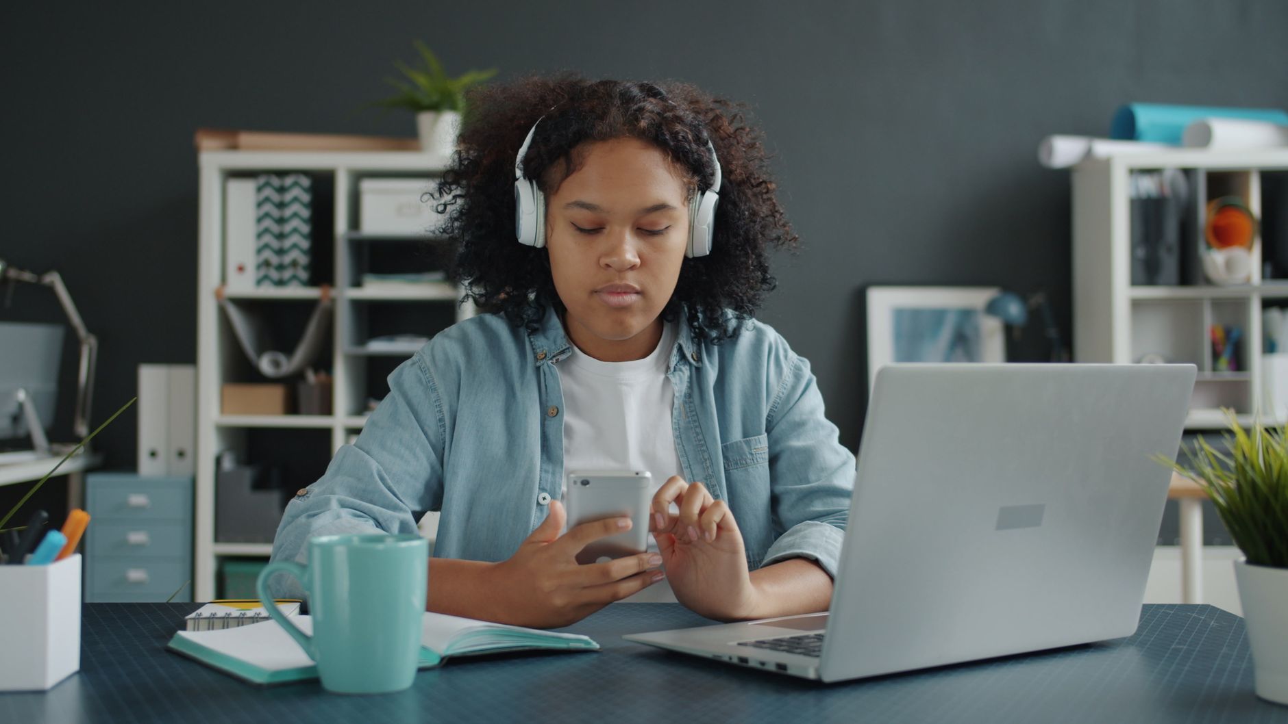 Person using a smartphone and laptop in a modern office