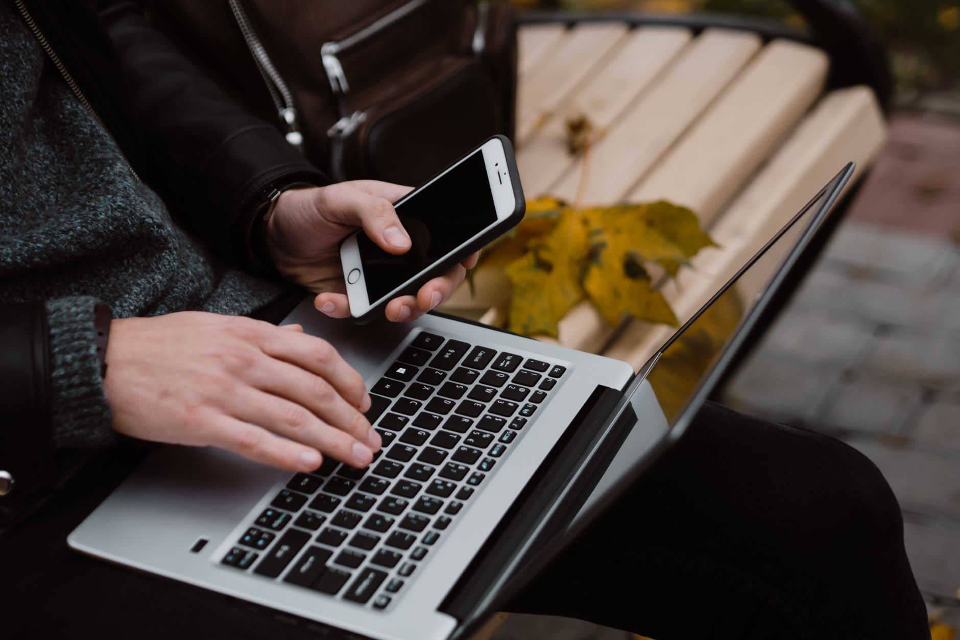 Person working remotely with a laptop and smartphone outdoors