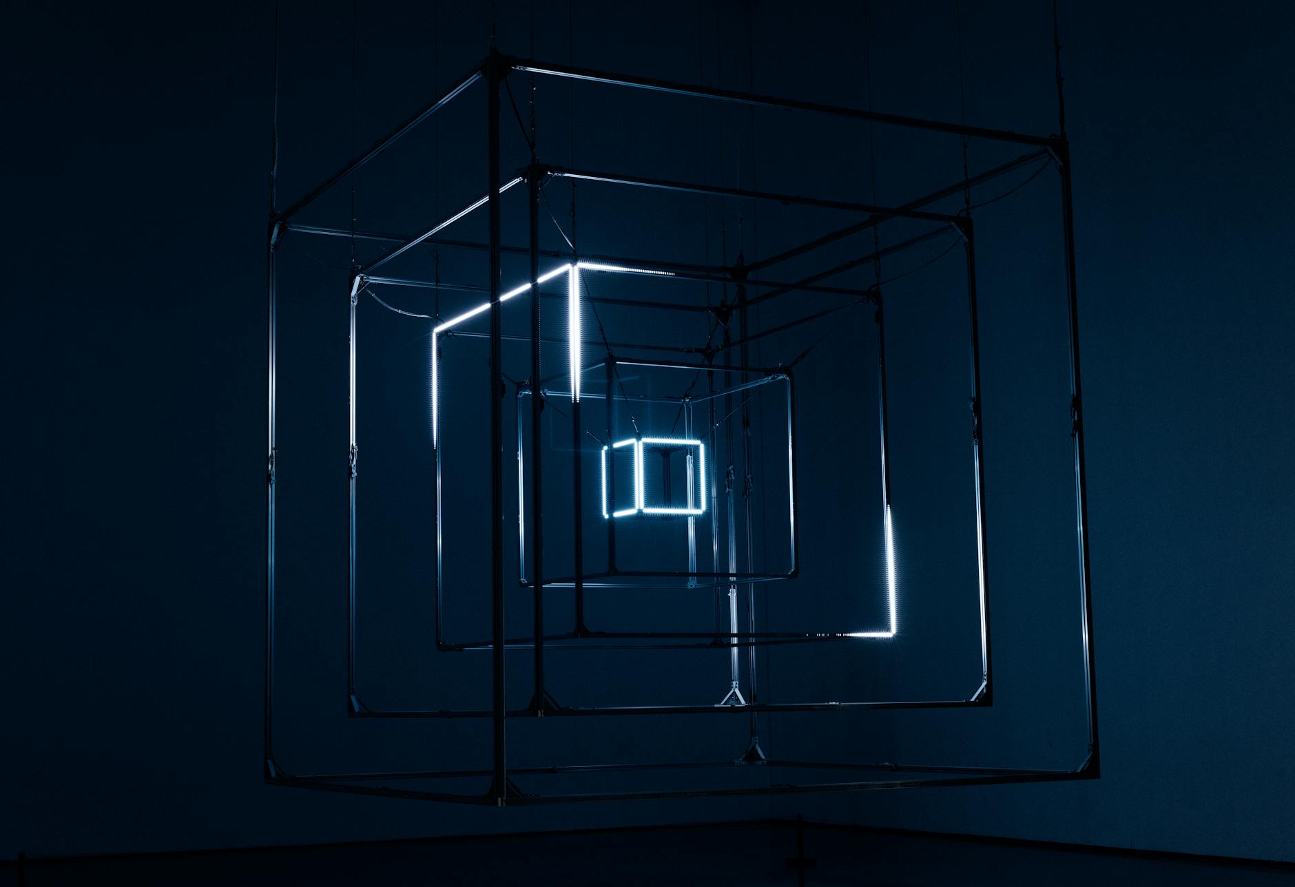 A captivating geometric light installation using cubes and neon lights against a dark background.