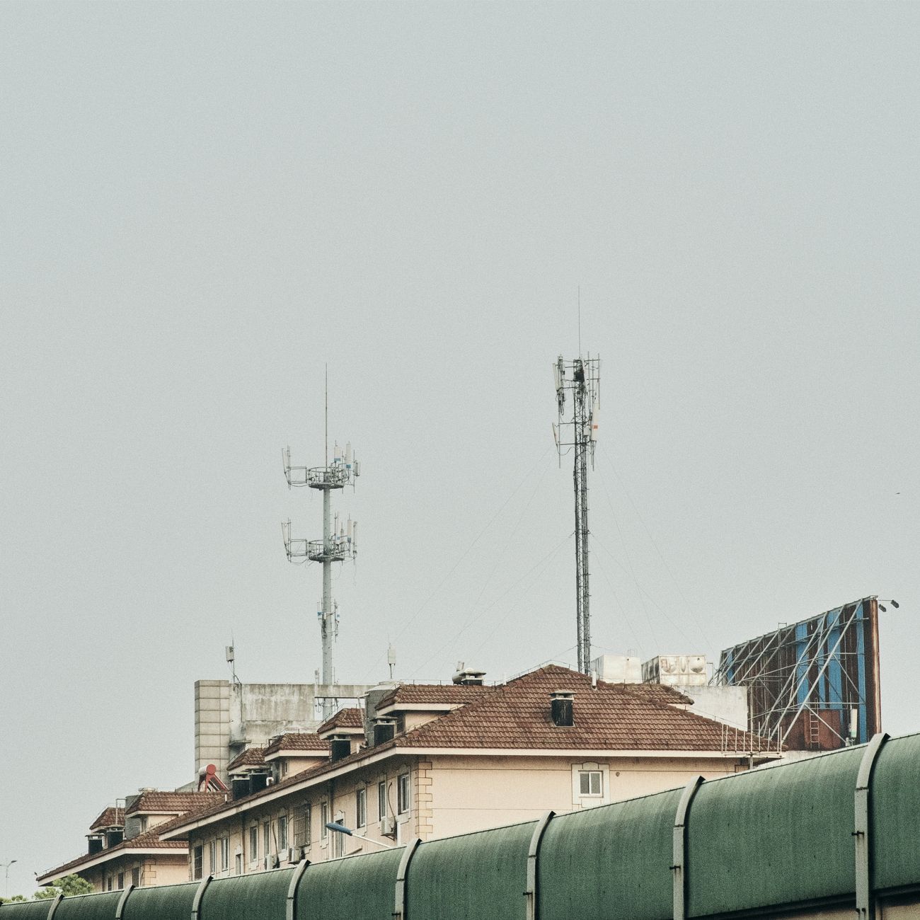 Photograph of a rooftop with antennas on a residential building under an overcast sky.