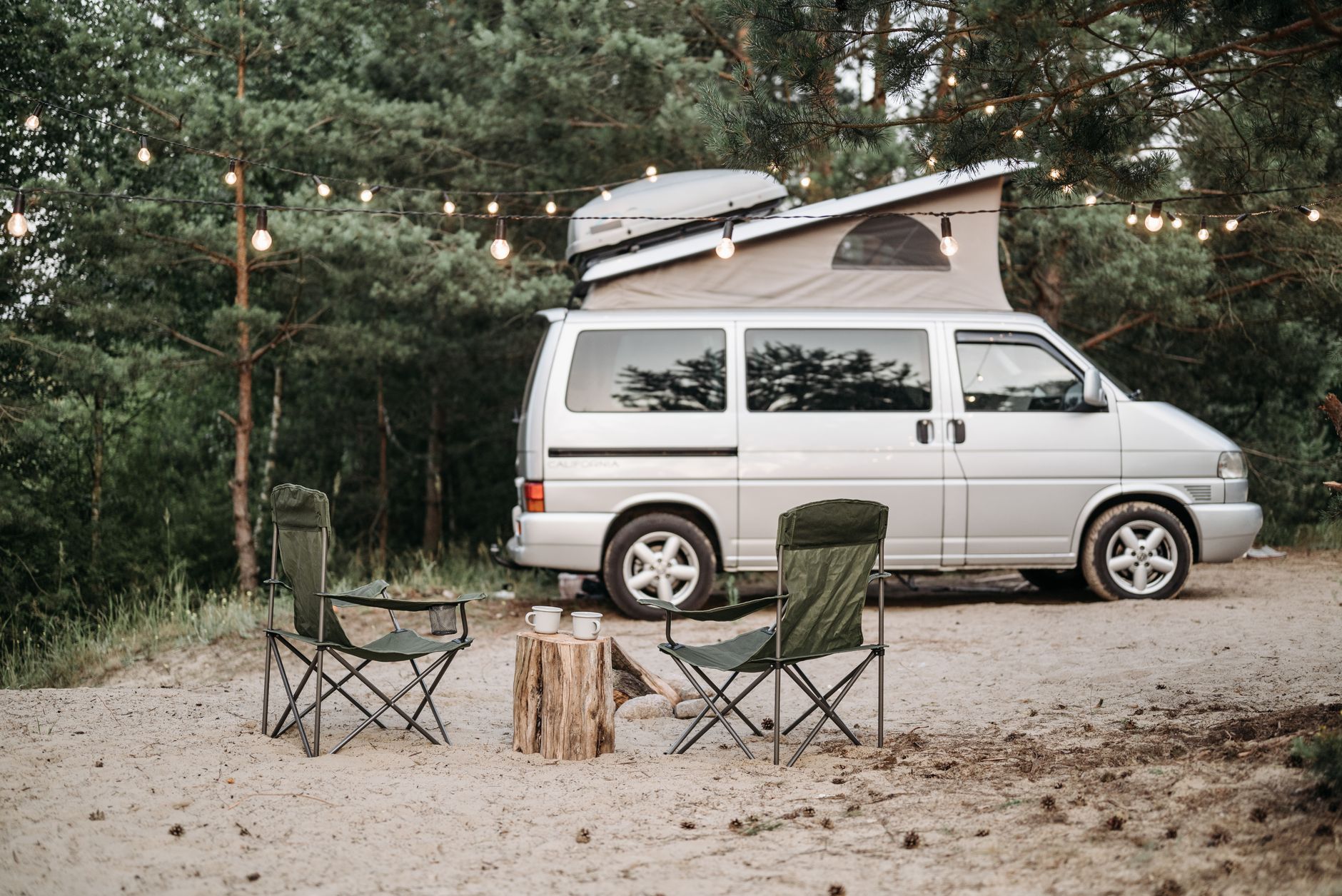 White camper van at a forest campsite, representing a portable Starlink setup