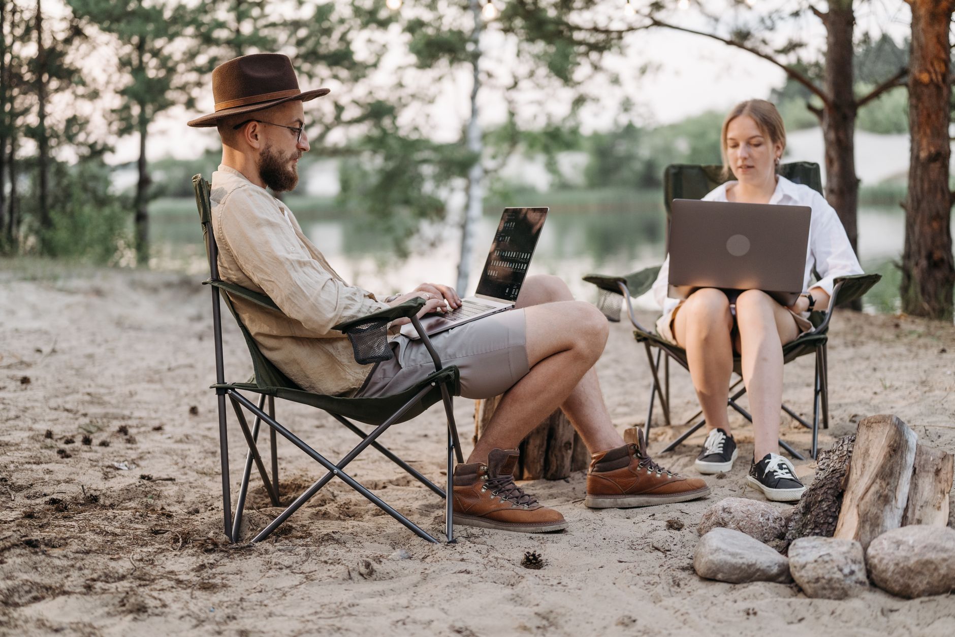 Two travellers using laptops at a campsite, illustrating portable Starlink Mini internet for remote work