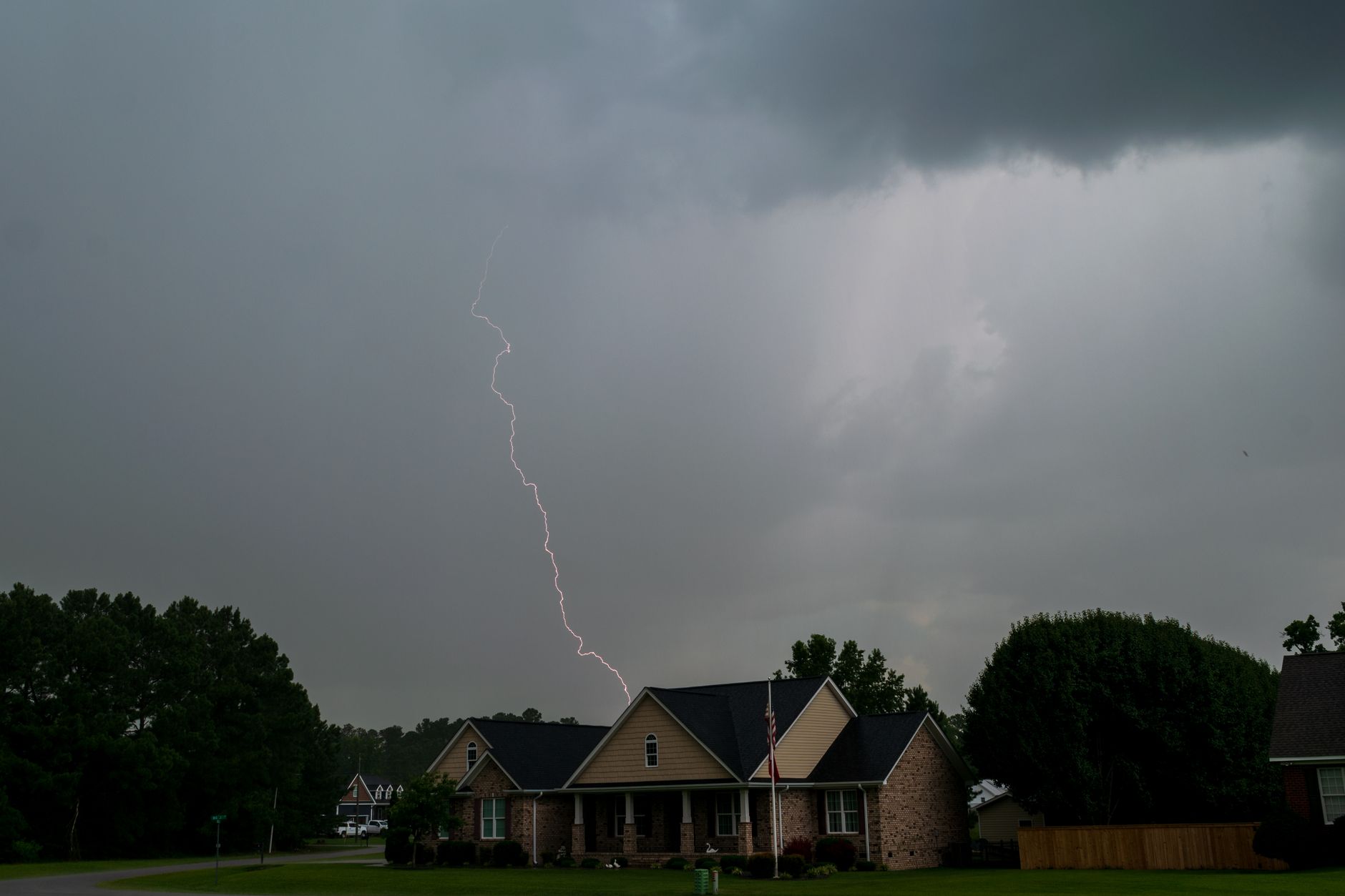 Lightning over houses during a thunderstorm, illustrating surge and storm preparation for Starlink