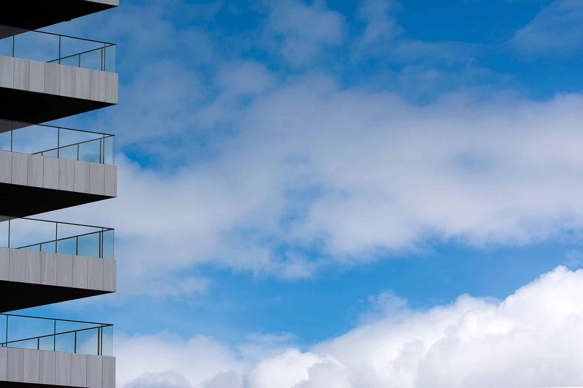 Modern apartment balconies beneath a blue sky with clouds
