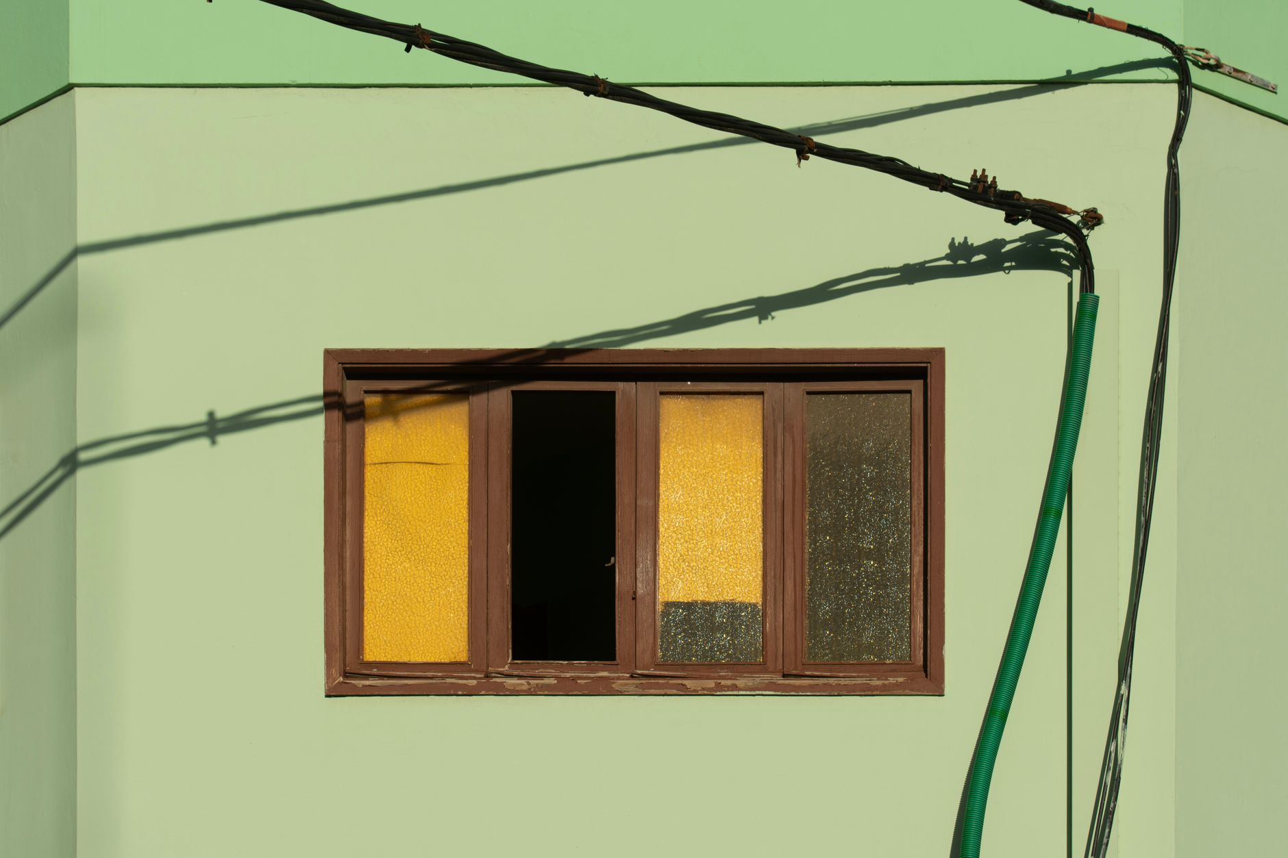 Green building facade with a wooden window and exterior cabling