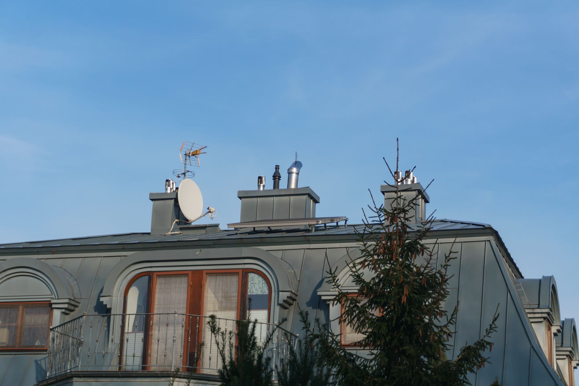 Roof-mounted satellite dish and antennas against a clear blue sky
