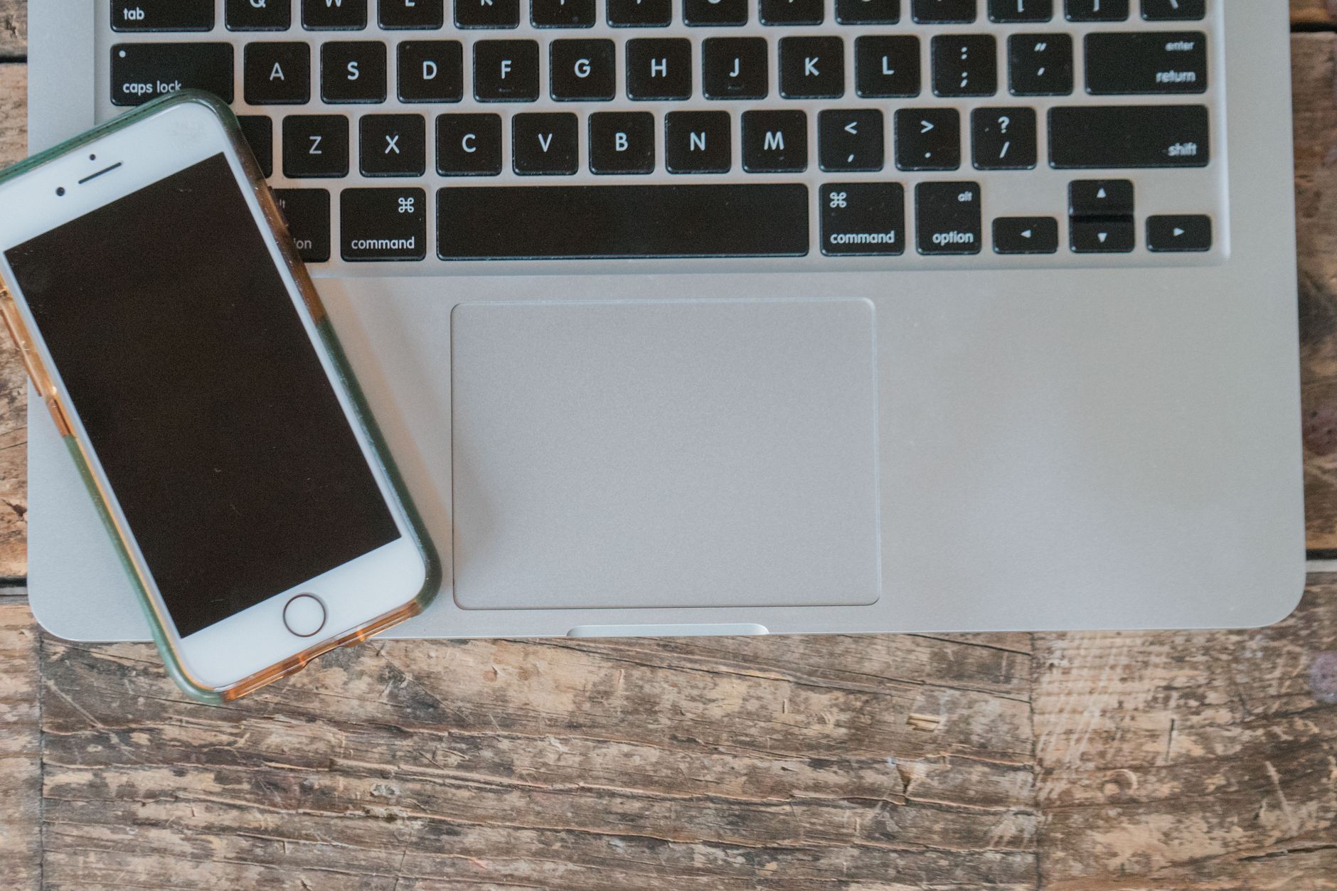Overhead view of a laptop and smartphone on a wooden desk, representing a backup internet connection.