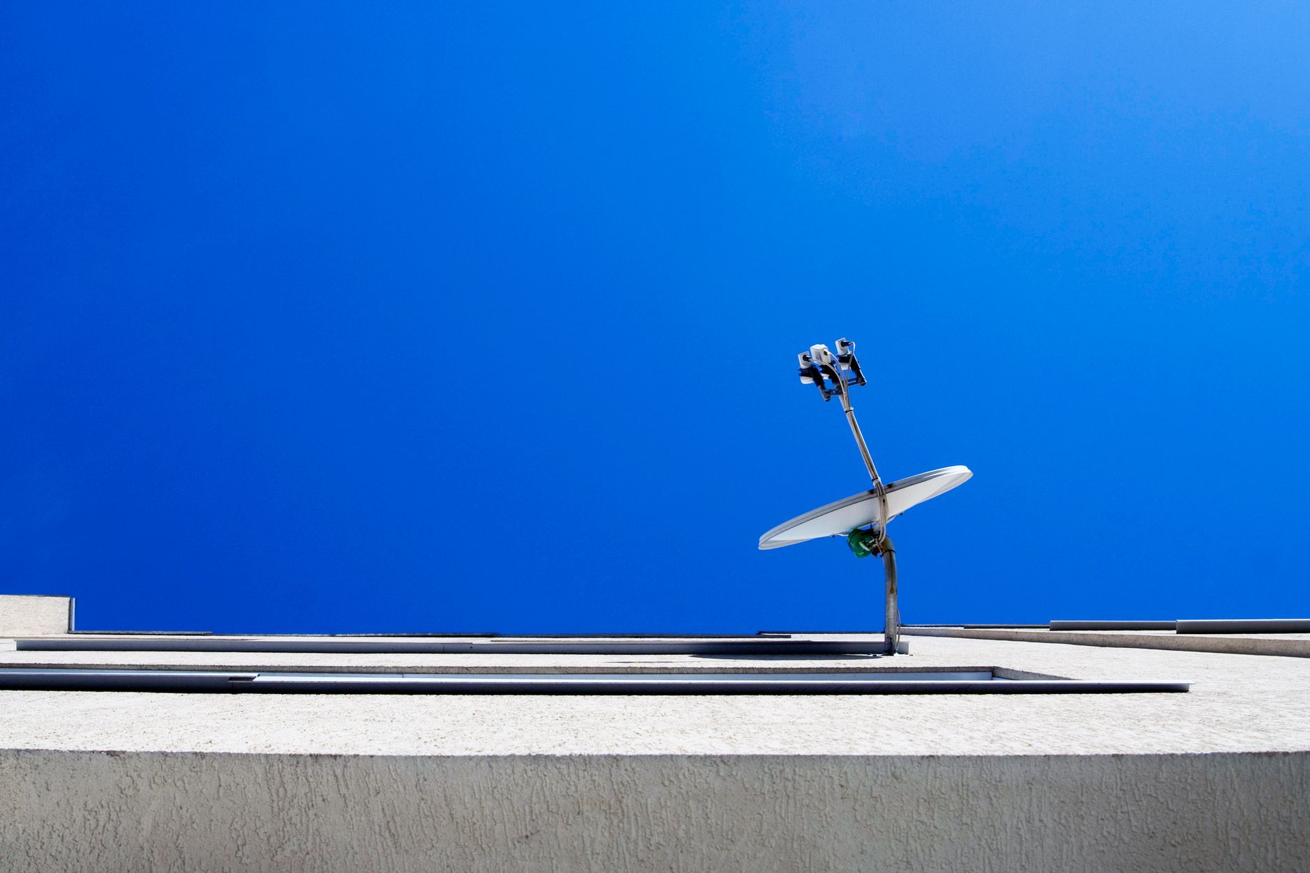 Satellite dish on a modern building against a clear blue sky