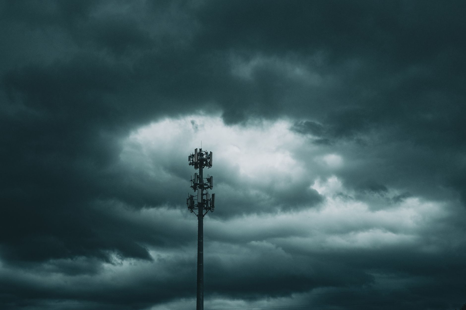 Cell tower beneath a cloudy sky; illustrative photograph of terrestrial mobile infrastructure, not a SpaceX site.