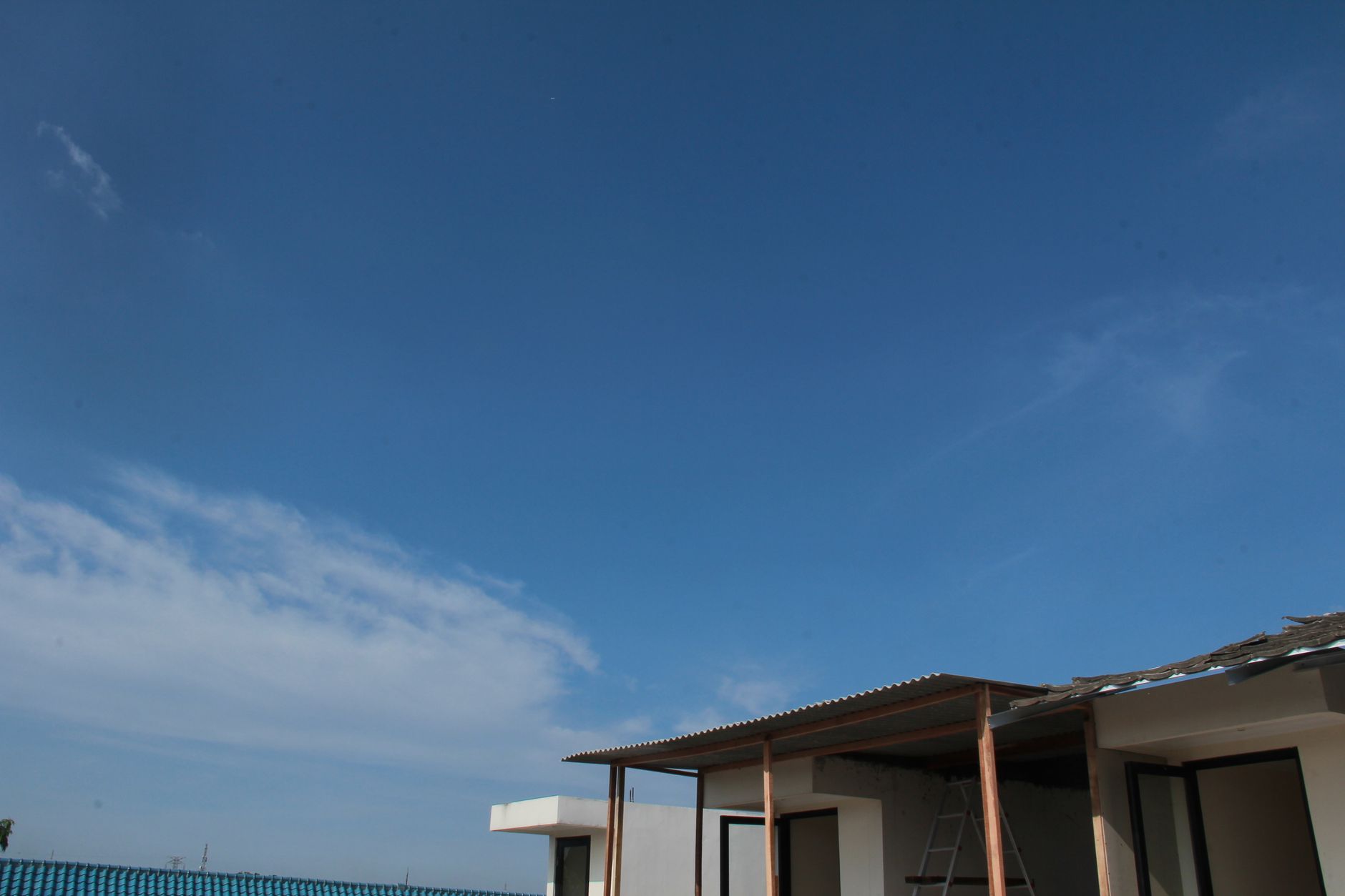 Clear sky above a house roof, illustrating a potential home installation location; no Starlink kit is pictured.